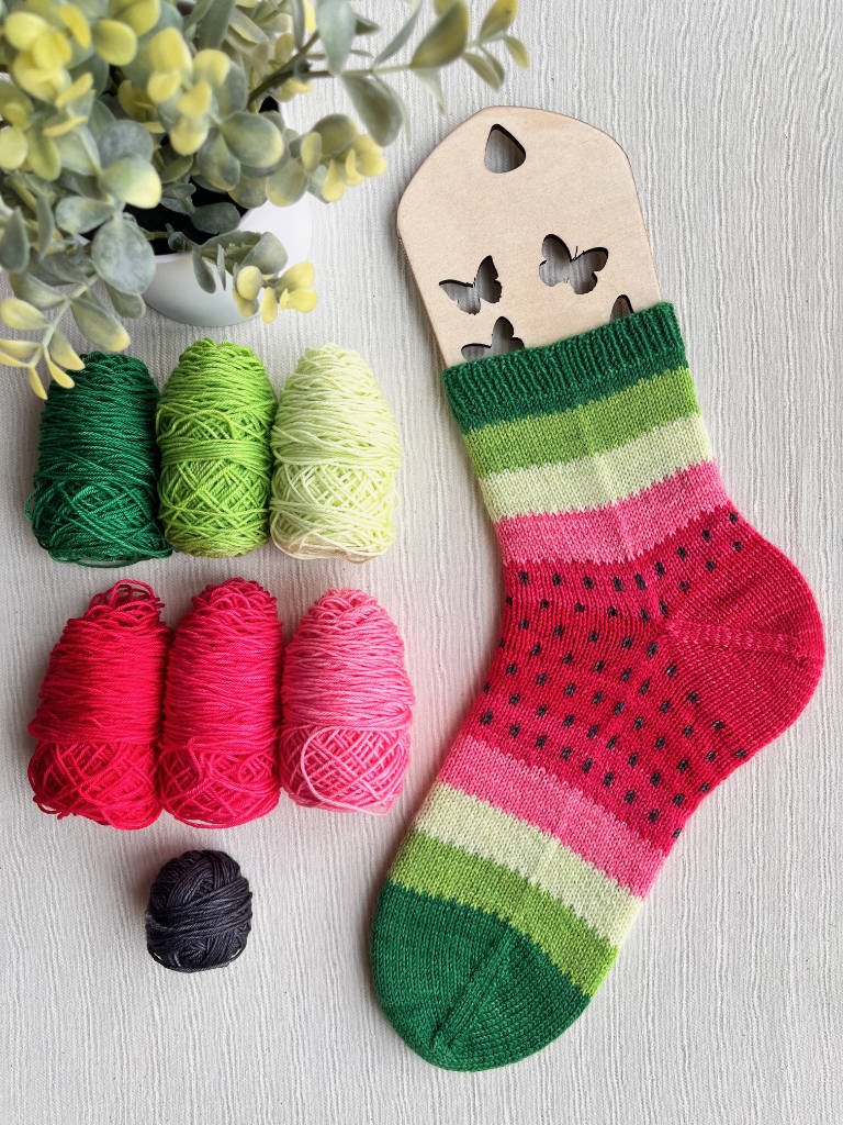 Hand knit sock with watermelon colors and yarn.